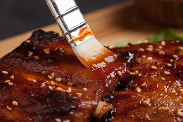 Chef spreading sauce bbq on ribs.