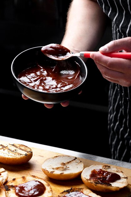 Chef spreidt saus op hamburgerbroodjes