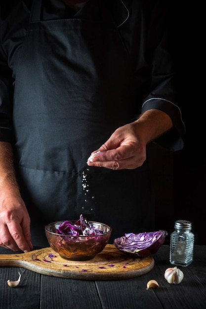 The chef sprinkles the salad with fresh red cabbage salt