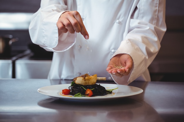 Photo chef sprinkling spices on dish