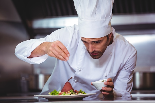 Chef sprinkling spices on dish