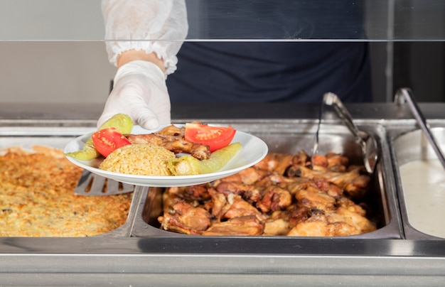 Chef in piedi dietro la stazione di servizio per il pranzo completo