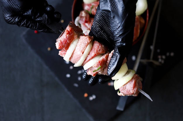 Lo chef ha incordato la carne per il barbecue su uno spiedino. kebab crudo. cucinare kebab.