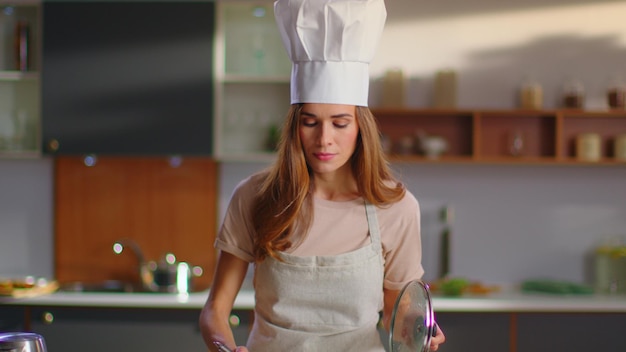 Chef tasting soup on kitchen Woman in uniform cooking soup on stove