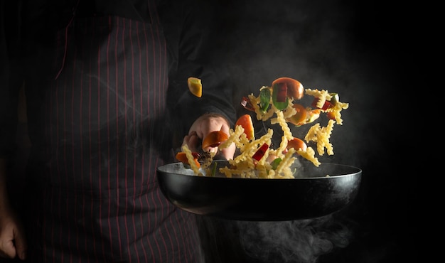 The chef throws food on a hot pan Space for advertising on a black background