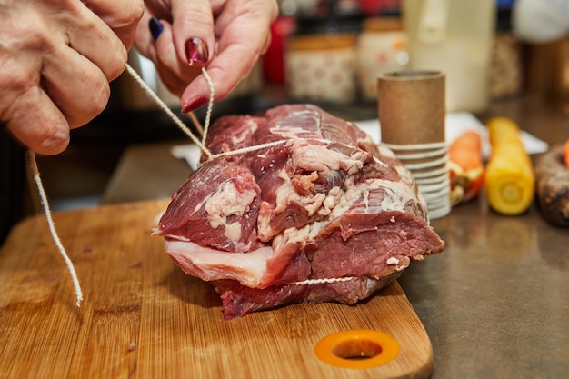 Chef ties the beef with rope and prepares it for baking in the oven