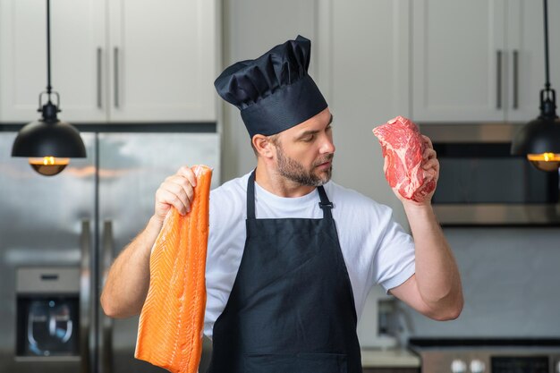 Chef in uniform cooking raw meat beef and fish salmon fillet in the kitchen restaurant menu concept