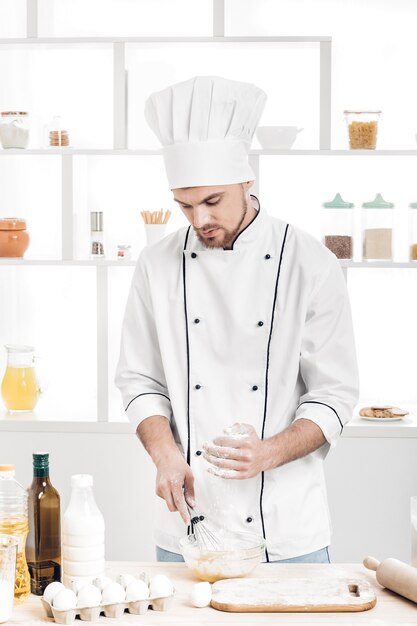 Шеф-повар в униформе делает тесто на кухне