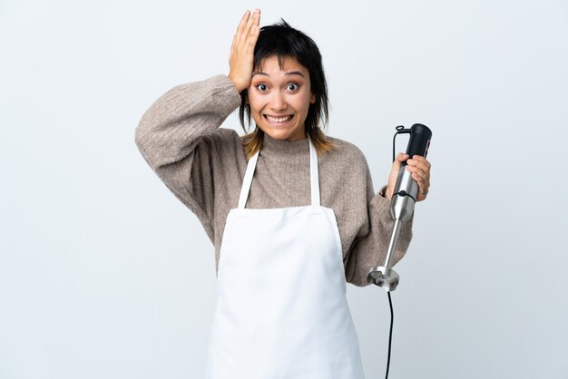 Chef Uruguayan girl using hand blender over isolated white with surprise facial expression