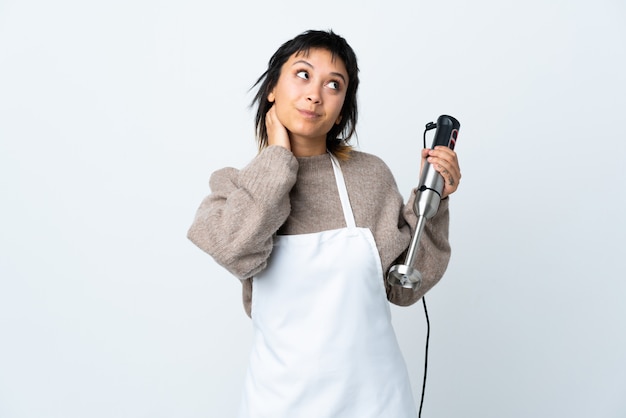 Chef Uruguayan girl using hand blender over white wall thinking an idea