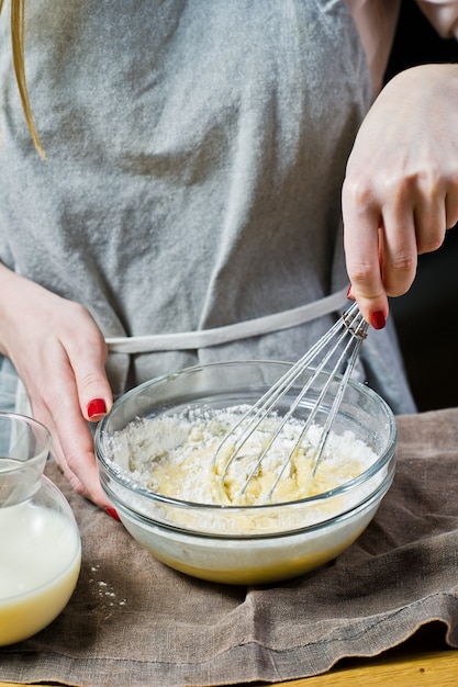 The chef whips gluten-free flour and eggs with oat milk in a bowl. 