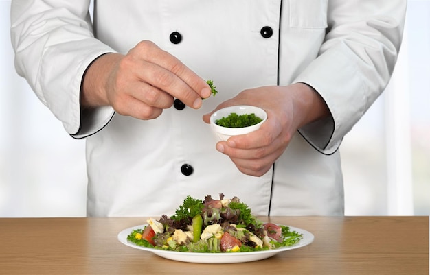 흰색 유니폼을 입은 요리사와 흰색 배경에 음식이 있는 접시