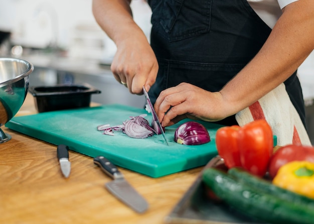 Foto chef con grembiule per affettare le verdure in cucina