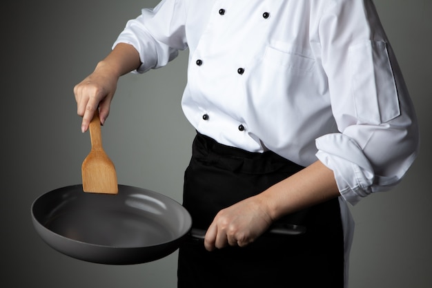 Фото Шеф-повар с рукой держать кастрюлю на сером фоне