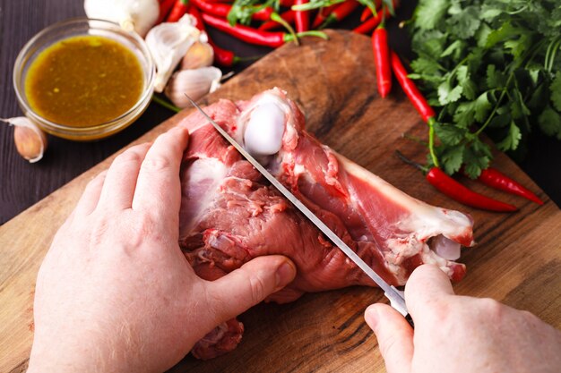 Chef with a knife in their hand cuts fresh meat on a table