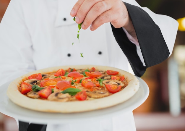 Chef with the pizza in foregroun in the restaurant pizza delivery