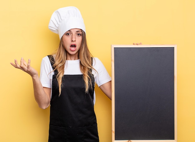 Chef woman feeling extremely shocked and surprised. blackboard menu concept