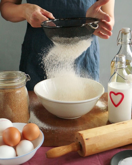 La donna dello chef sta setacciando la farina. cucina casalinga