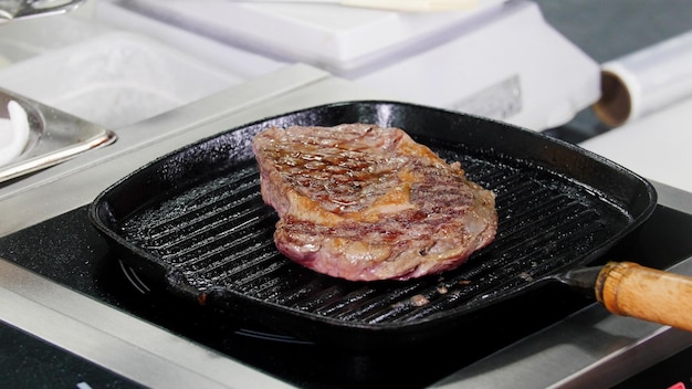 鍋でステーキを揚げるキッチンで働くシェフ