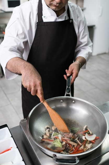 Lo chef lavora nella cucina del ristorante preparando il pasto