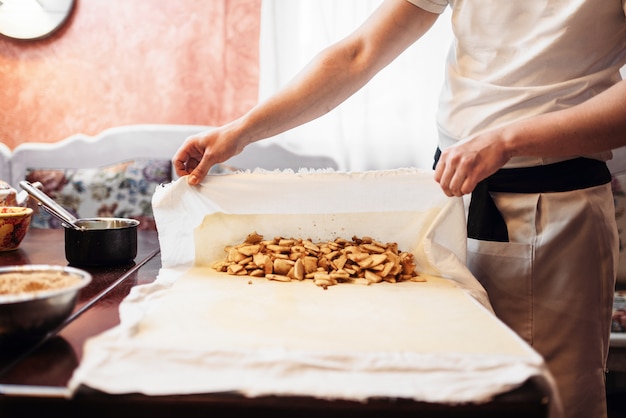 Foto lo chef avvolge il ripieno in pasta, strudel di mele