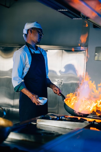 Chefhanden beheren vlammen wok in een professionele keuken Close-up van culinaire vaardigheden vlammen koken voedsel Bezige chef hanteert vlammen in een moderne keuken om voedsel te koken met vuur