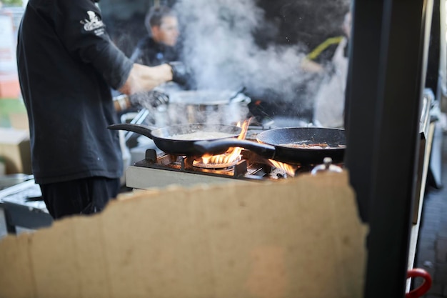 chefs cook in a wok pan in the kitchen Smoke comes out of the pan