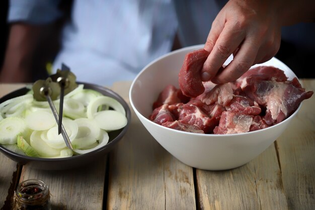 シェフの手が玉ねぎと肉のケバブを準備しています