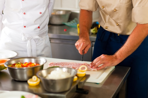 Chefs preparing fish in restaurant or hotel kitchen