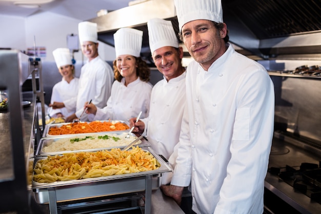 Chefs standing at serving trays of pasta