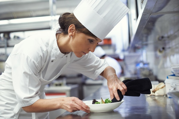 Foto chef al lavoro inquadratura di uno chef che mette gli ultimi ritocchi su un piatto in una cucina professionale