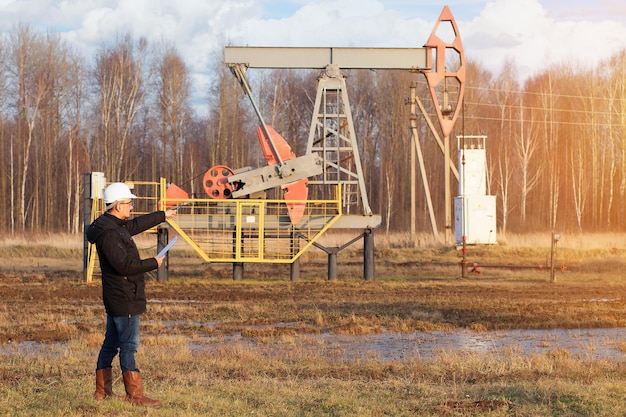 A chemical engineer with a tablet in his hands points to an oil rocking chair. Autumn sunset