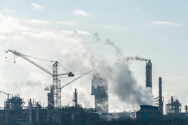 Chemical industry Environmental pollution by harmful emissions into the atmosphere Poisonous smoke comes from the big pipes The factory poisons nature Silhouette of pipes and smoke Sunny day