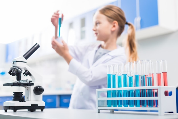 Chemical liquids. Selective focus of chemical reagent dividing into vials which standing in stand and placing near microscope