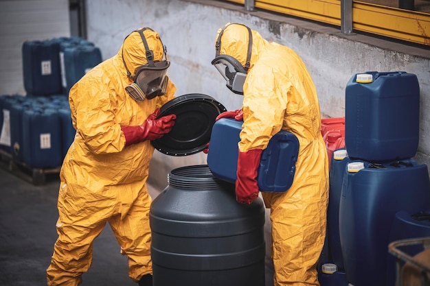 Chemical plant workers in hazmat suit mixing chemicals and manufacturing acids for heavy industry