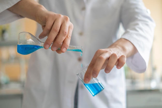 Chemical researcher work with two beakers with blue liquid b