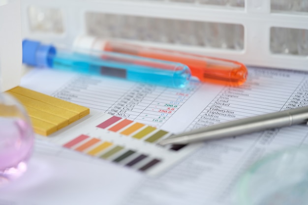 Chemical test tubes with blue and orange liquid with analysis results on table laboratory