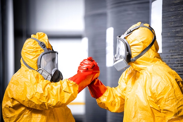 Chemicals workers in protection suit gas mask and gloves celebrating success at job