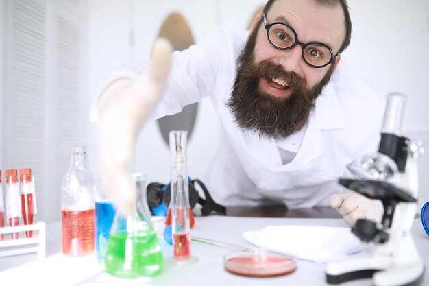 Chemicus gek Een gekke wetenschapper voert experimenten uit in een wetenschappelijk laboratorium Doet onderzoek met behulp van een microscoop