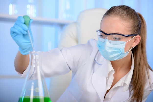 Chemicus vrouw testmonster van vloeistof in laboratorium.