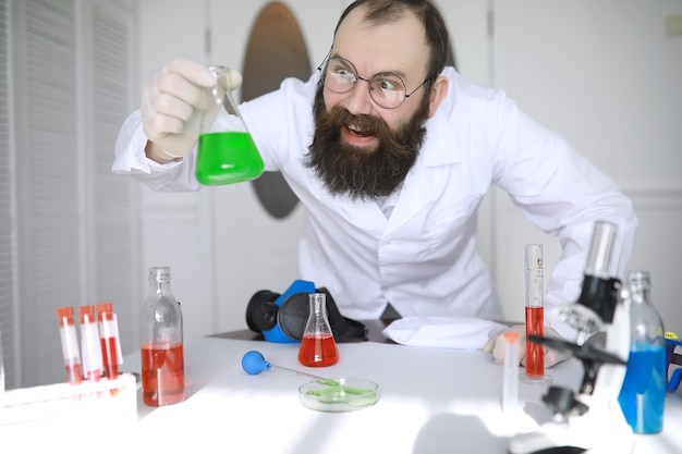 Chimico pazzo. uno scienziato pazzo conduce esperimenti in un laboratorio scientifico. esegue ricerche utilizzando un microscopio.