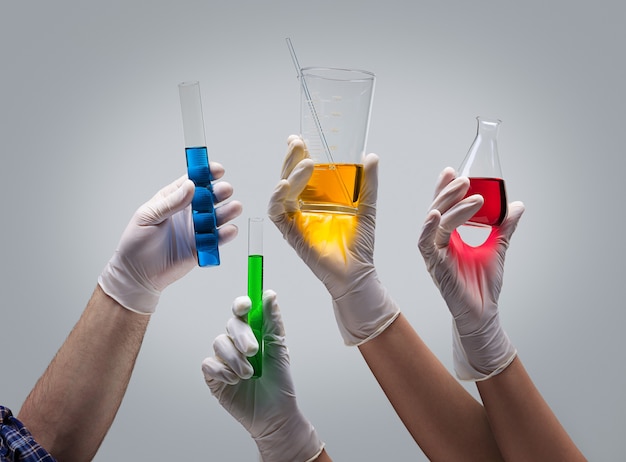 Chemist hands holding laboratory glassware with liquids