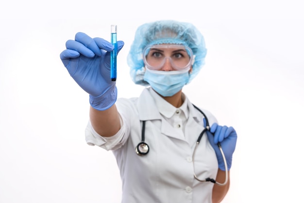 Chemist in protective uniform holding and examining test tube with blue vial substance isolated on white. Woman scientist making experiment