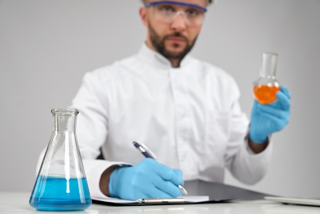 Chemist taking notes while holding flask