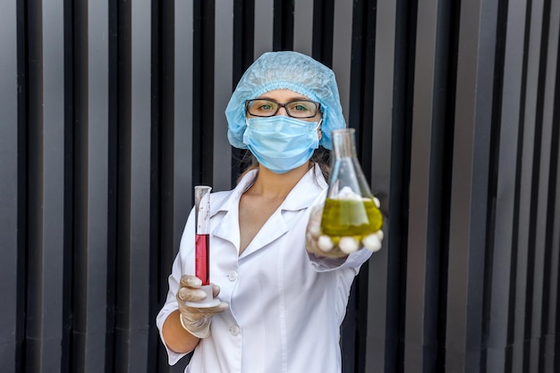 Chemist with flask making scientific experiment. She's in protective uniform and gloves