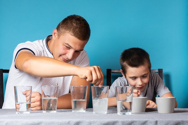 Chemistry education and study concept. Dad and her son stirs measuring spoon the mixture into a container with chemical elements, for experiments at home