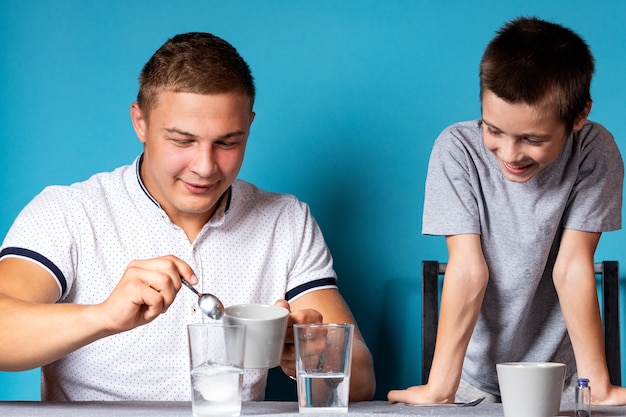 Chemistry education and study concept. Dad and her son stirs measuring spoon the mixture into a container with chemical elements, for experiments at home