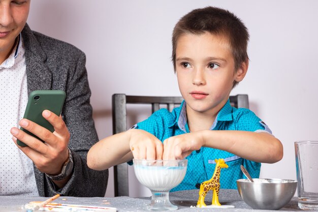 Chemistry education and training concept. Close-up of a boy and his dad making a home experience, making a non-Newtonian liquid from starch and water