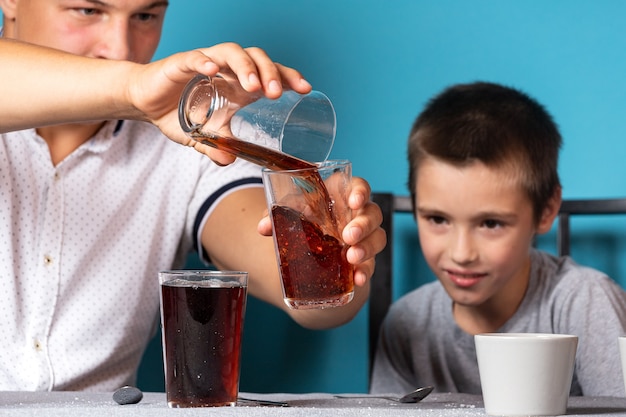 Istruzione chimica e concetto di formazione. primo piano di un ragazzo e di suo padre, gli scienziati versano il permanganato di potassio in una provetta per un esperimento con un cambiamento di colori, esperimenti a casa