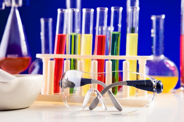 Chemistry lab equipment on a table over blue background. Glassware and biology equipment